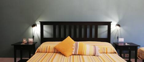 Una cama con ropa de cama a rayas, un cabecero de madera y dos mesitas de noche con lámparas.