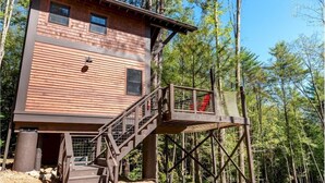 A wooden cabin with a balcony and a staircase leading to a deck. - Forest Hill Lodge & Cabins (Lake George)