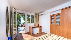 Een slaapkamer met een bed, een bureau, een kledingkast en een glazen schuifdeur die uitkomt op een buitenruimte.