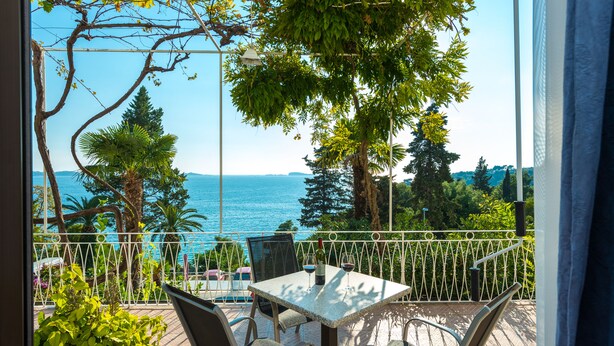 Een terras buiten met een tafel en stoelen, met uitzicht op een waterpartij.