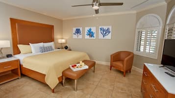 A hotel room with a bed, a chair, a TV, and artwork on the wall.