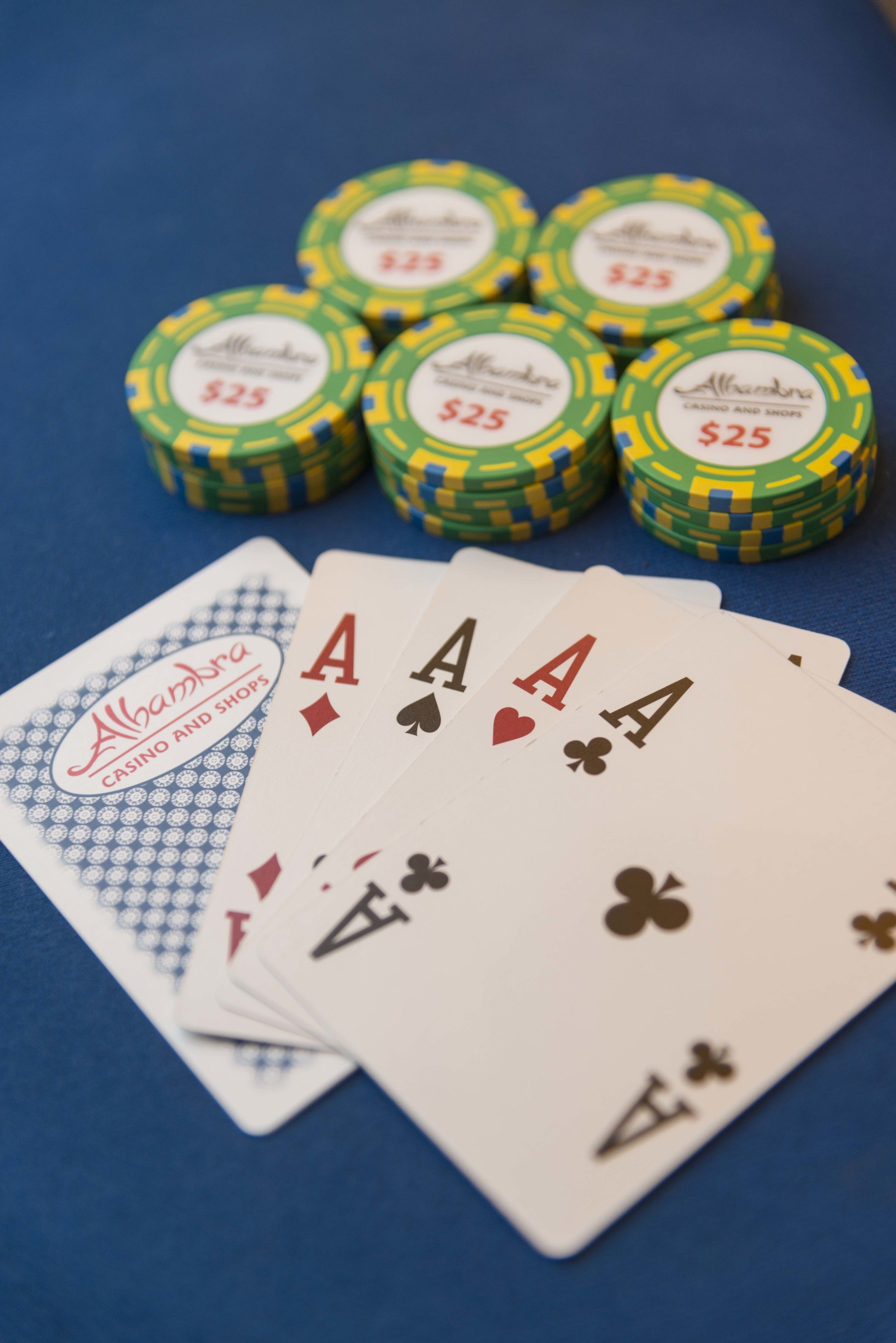 Una mesa azul con cuatro cartas y seis fichas de póker etiquetadas $25.