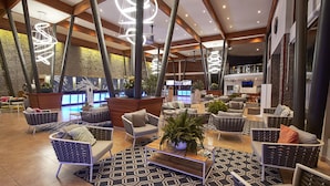 A spacious lobby with modern furniture, a central coffee table, and a large, decorative light fixture.