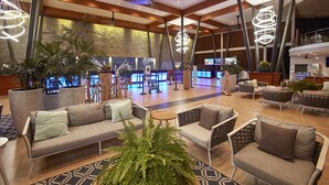 A spacious lobby with a modern design, featuring sofas, chairs, and a large potted plant.