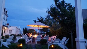 Un espace extérieur aménagé avec des chaises Adirondack et un grand parasol, sous une enseigne indiquant « National Hotel Fireside ».
