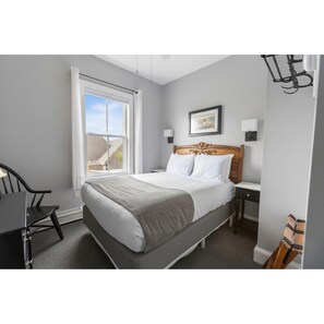 Une chambre à coucher avec un lit, un bureau, une chaise, une fenêtre et un tableau au mur.