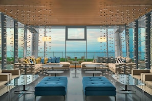 A modern lounge with sofas and tables, large windows, and hanging lights. - Four Points by Sheraton Oran (Oran)