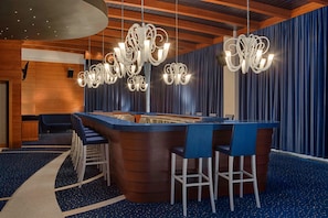 Experience the inviting atmosphere of our hotel lobby, featuring a central bar area with a curved countertop and comfortable seating.