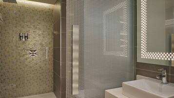 Un baño moderno con cabina de ducha acristalada, un espejo grande y un lavabo blanco.
