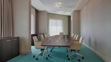 Un salón de conferencias con una gran mesa, sillas, un armario y una araña.