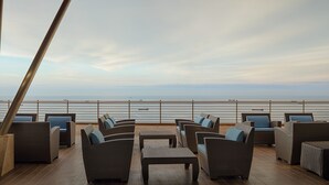 A deck with wicker furniture and a view of the sea.
