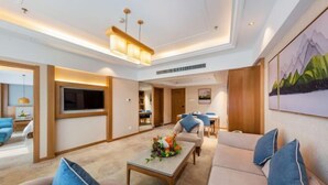 A modern living room with a sofa set, a coffee table with a floral arrangement, and a television. - Blue Horizon Hotel (Fuqian Street Dongcheng Dongying) (Dongying)