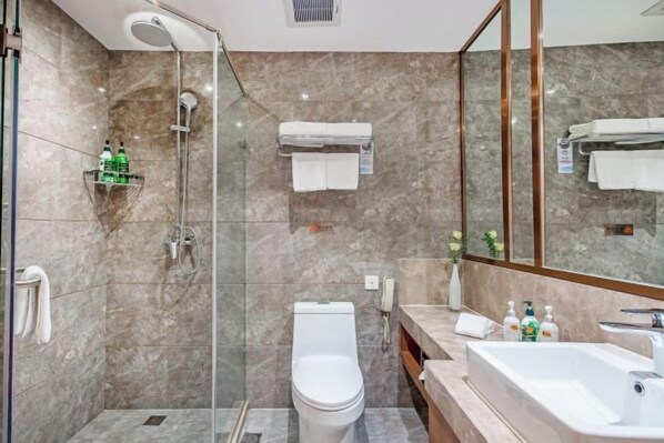 Un baño moderno con ducha envuelta en vidrio, un inodoro blanco, un lavamanos y un espejo.