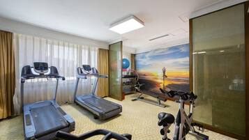 A hotel room with a treadmill, stationary bike, and elliptical machine.