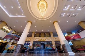 Un'ampia hall con una fontana centrale, soffitti alti e imponenti colonne.