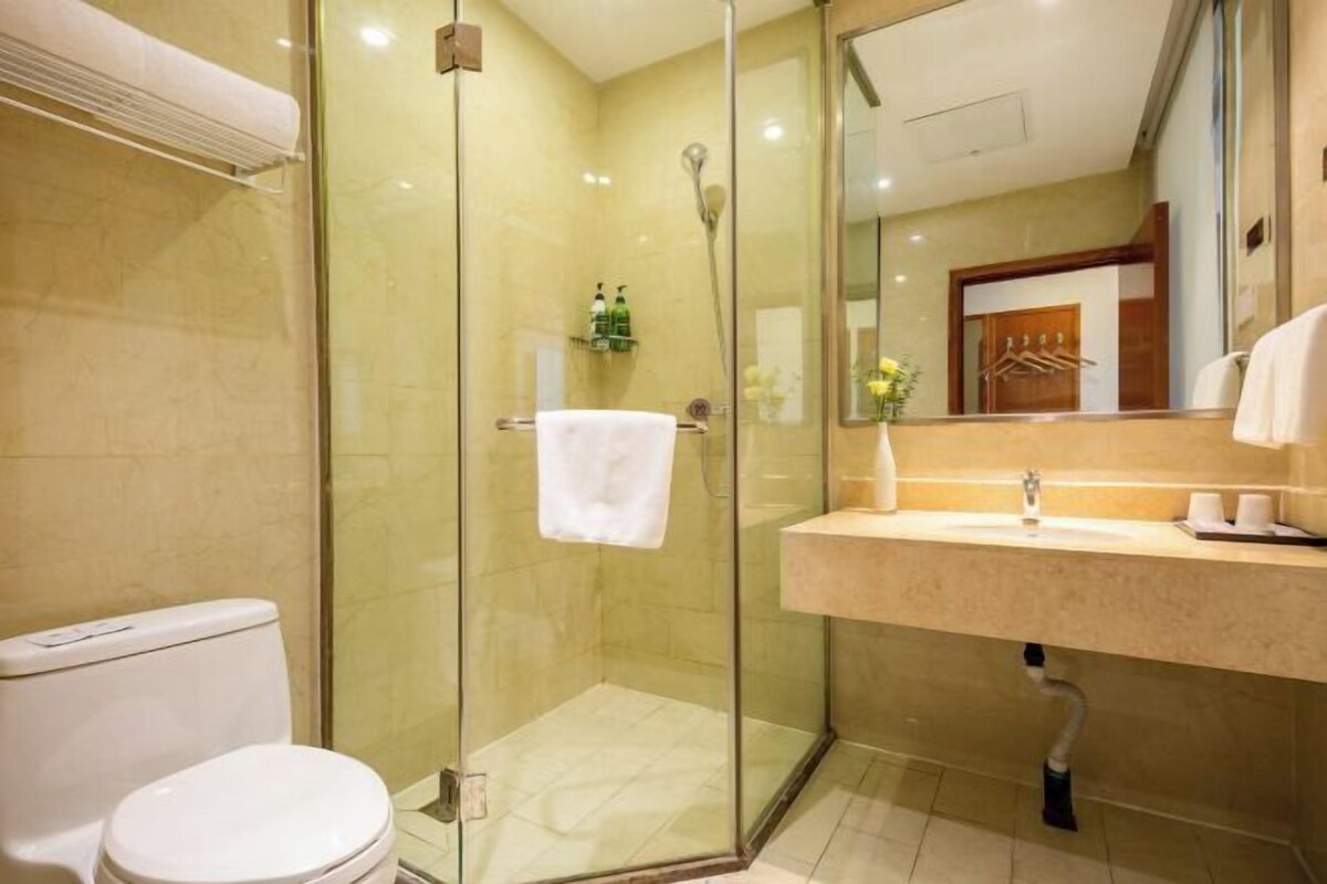 A modern bathroom with a glass-enclosed shower, a white toilet, and a vanity with a mirror.