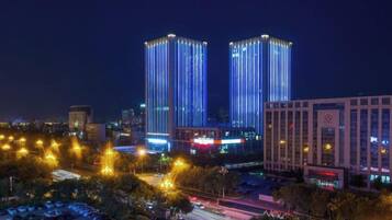 A cityscape at night with illuminated buildings and a parking area.