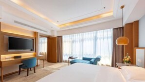 A hotel room with a large bed, a desk with a chair, a television, and a window with curtains. - Blue Horizon Hotel (Fuqian Street Dongcheng Dongying) (Dongying)