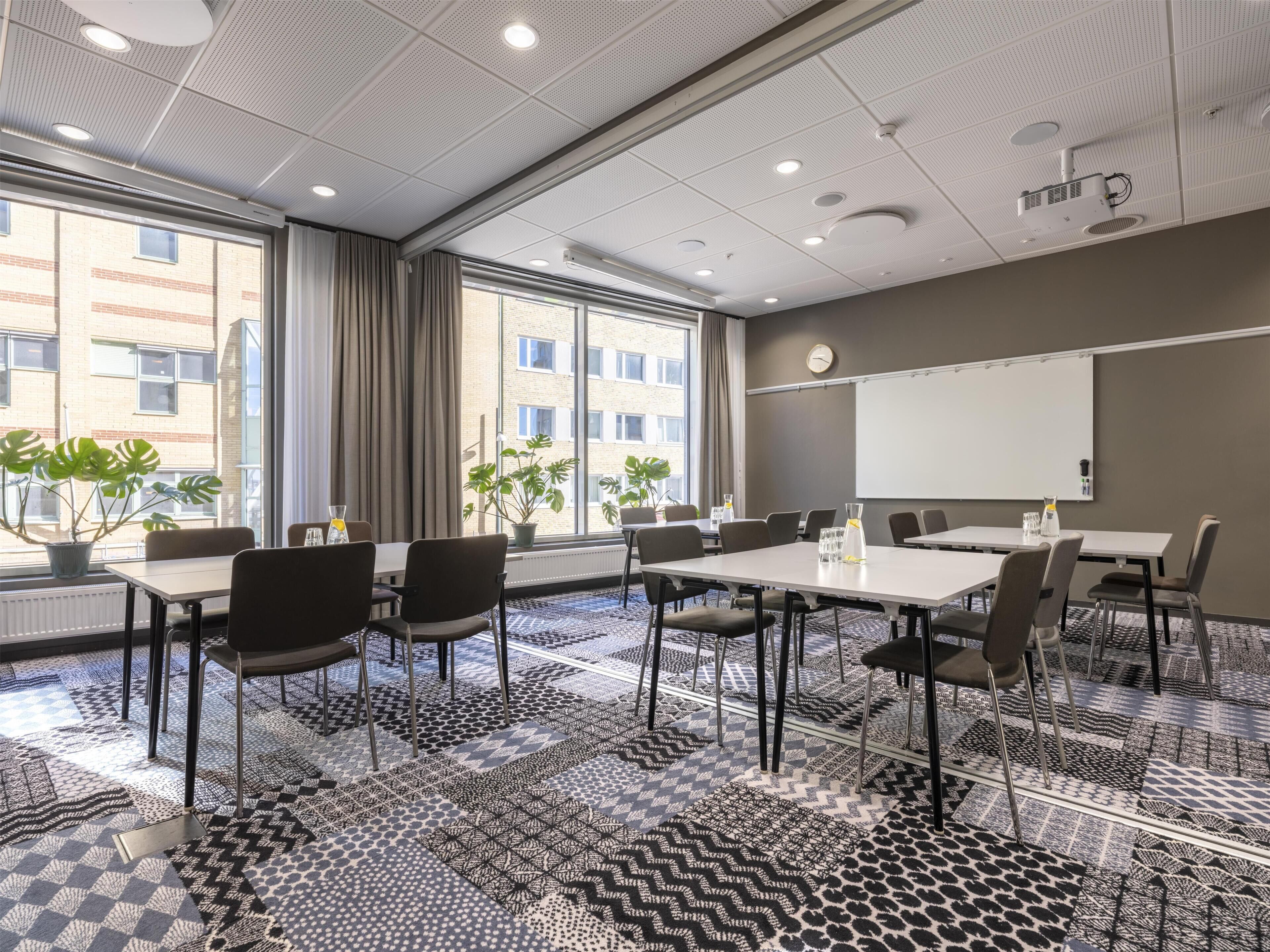 A conference room with a whiteboard, projector, and large windows with curtains.
