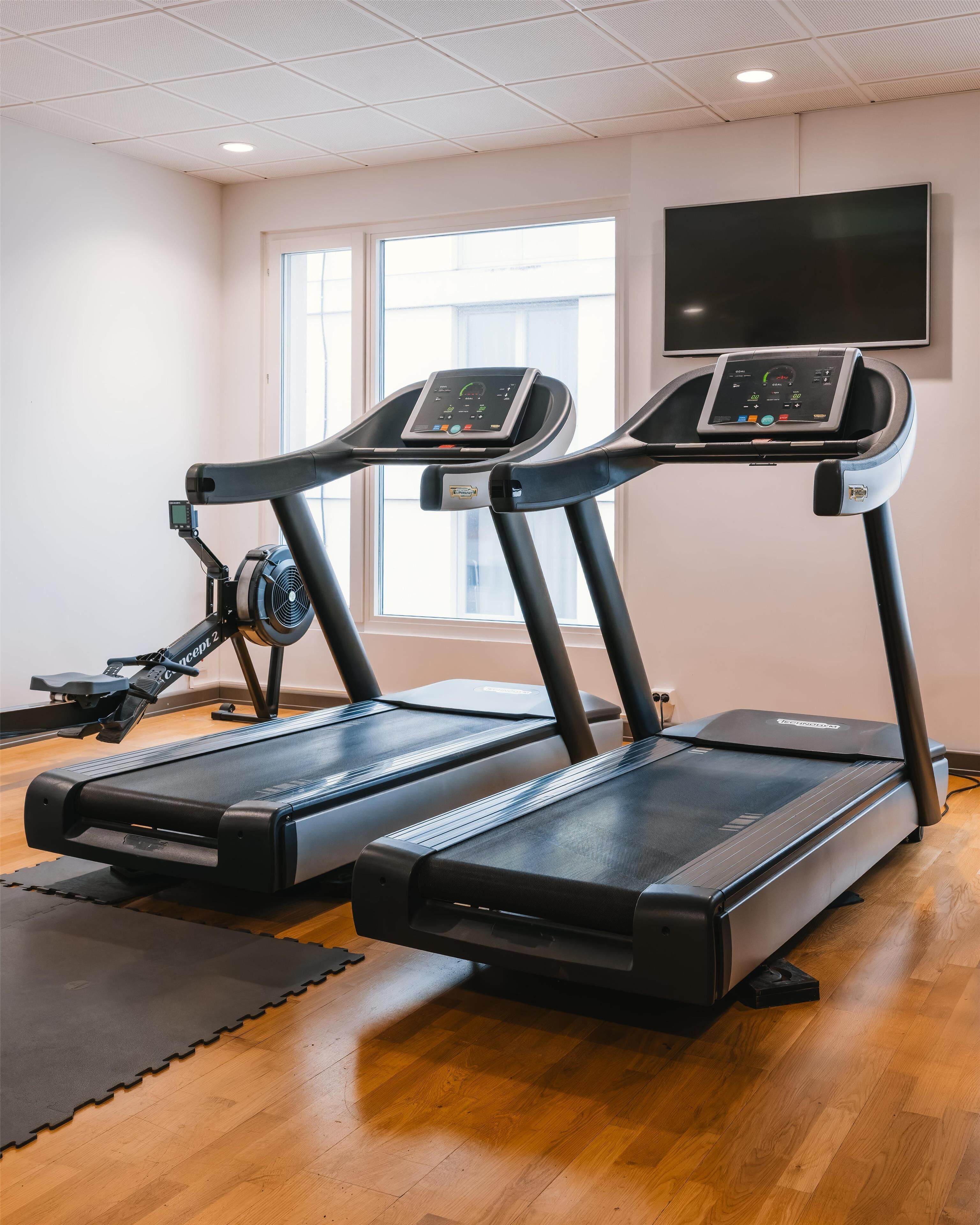 A gym with two treadmills, a stationary bike, and a large window.