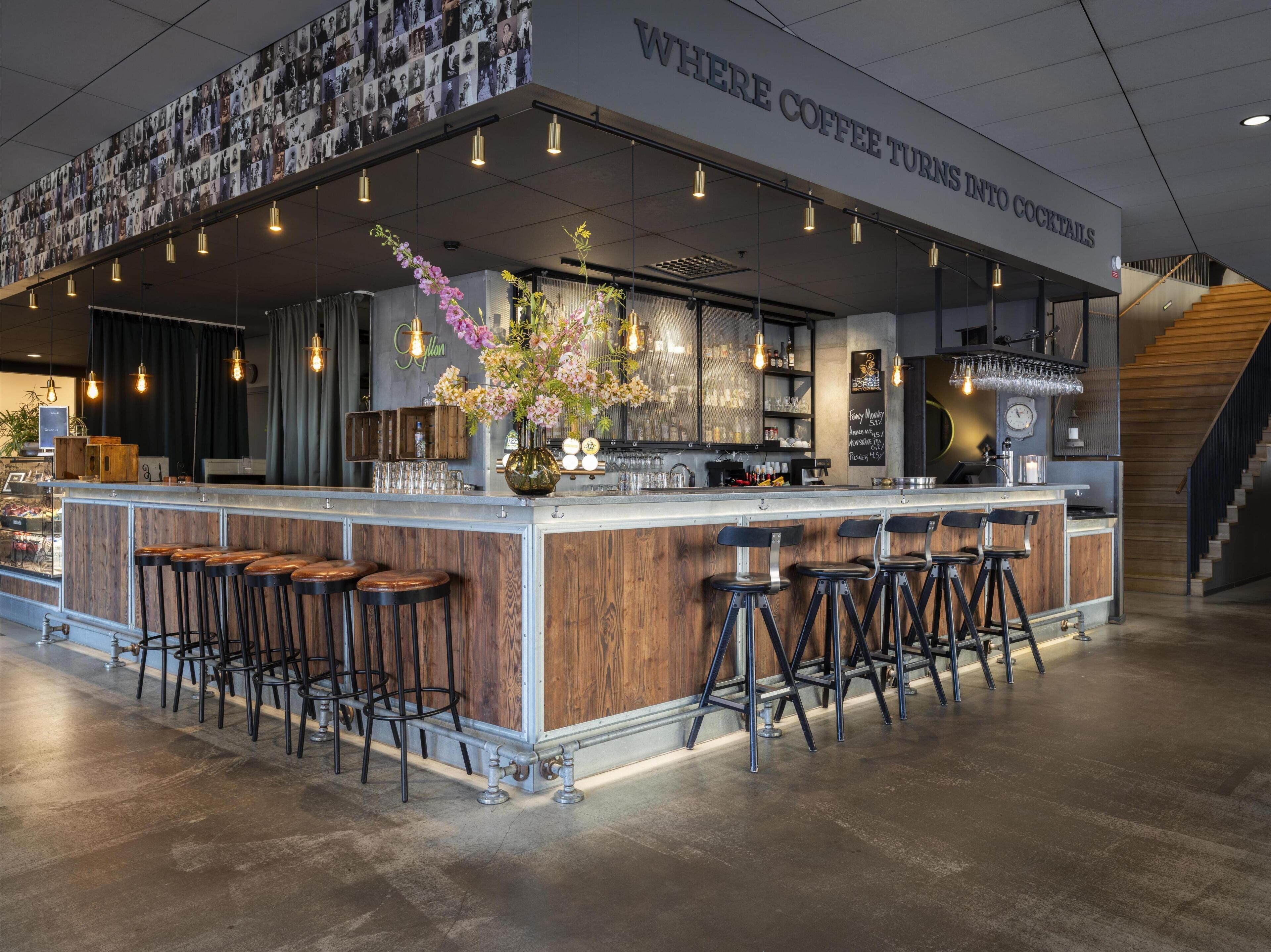 A bar area with a counter, stools, and a wall displaying photos.