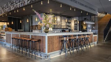 Un área de bar con mostrador, taburetes y una pared con fotografías.