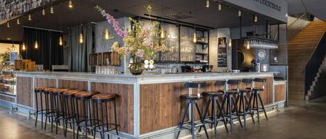 A bar area with a counter, stools, and a wall displaying photos.