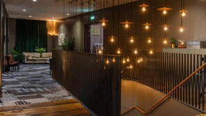 A modern hotel lobby with a wooden staircase, a patterned carpet, and pendant lighting. - Radisson Blu Metropol Hotel, Helsingborg (Helsingborg)