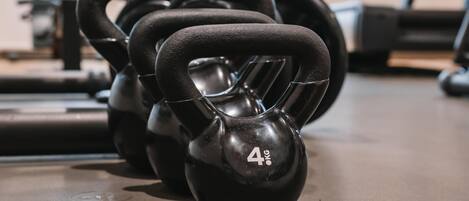 Un juego de mancuernas negras con la etiqueta de 4 kilogramos sobre el suelo de un gimnasio.