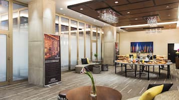 A modern hotel lobby with a round dining table, comfortable seating, and a large poster.