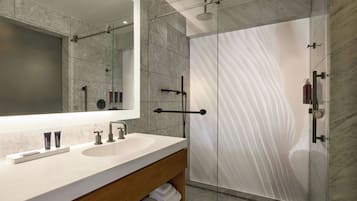 Un baño moderno con un espejo grande, lavamanos dobles y cabina de ducha con paredes de vidrio.