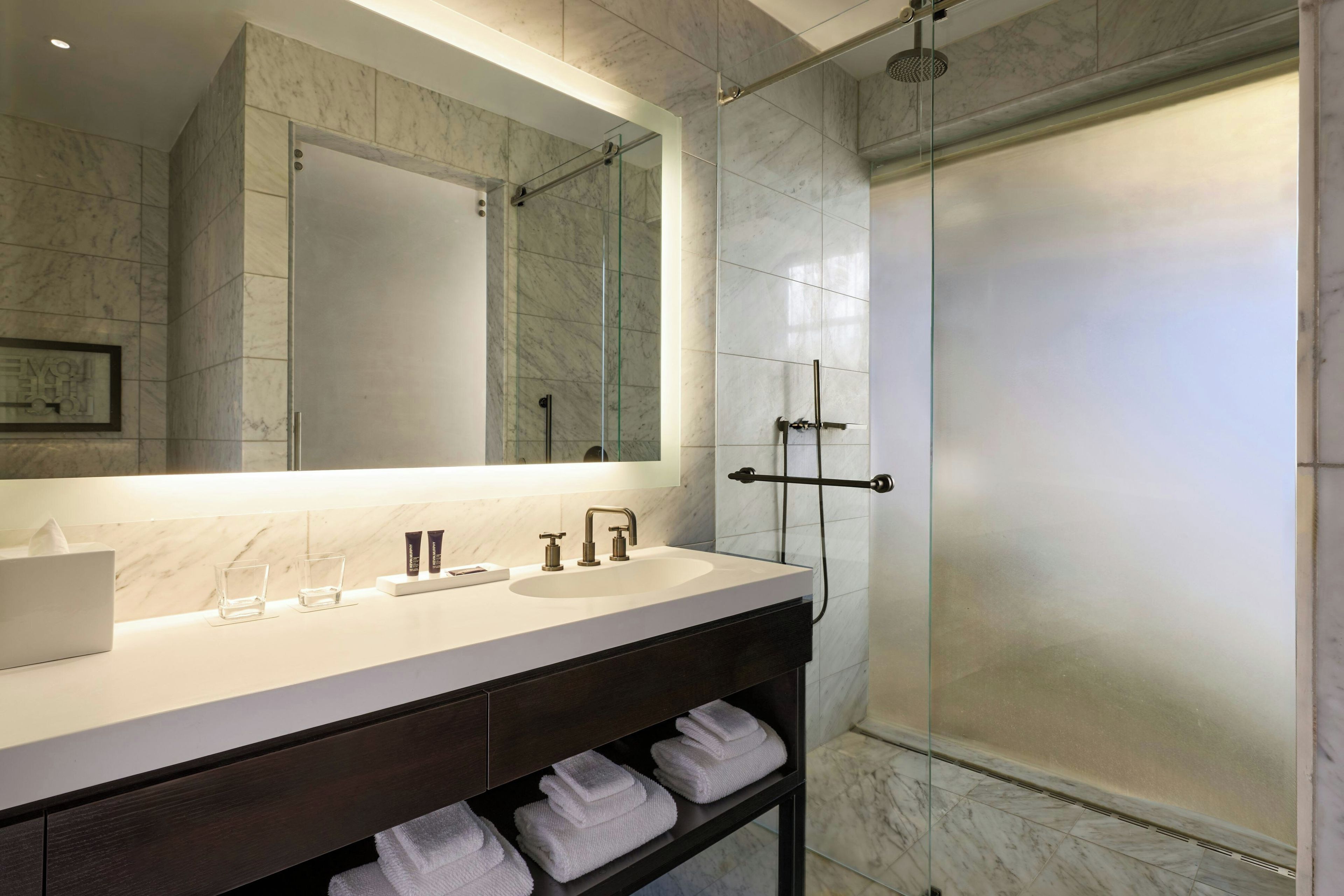 A modern bathroom with a large mirror, a sink, and a shower.