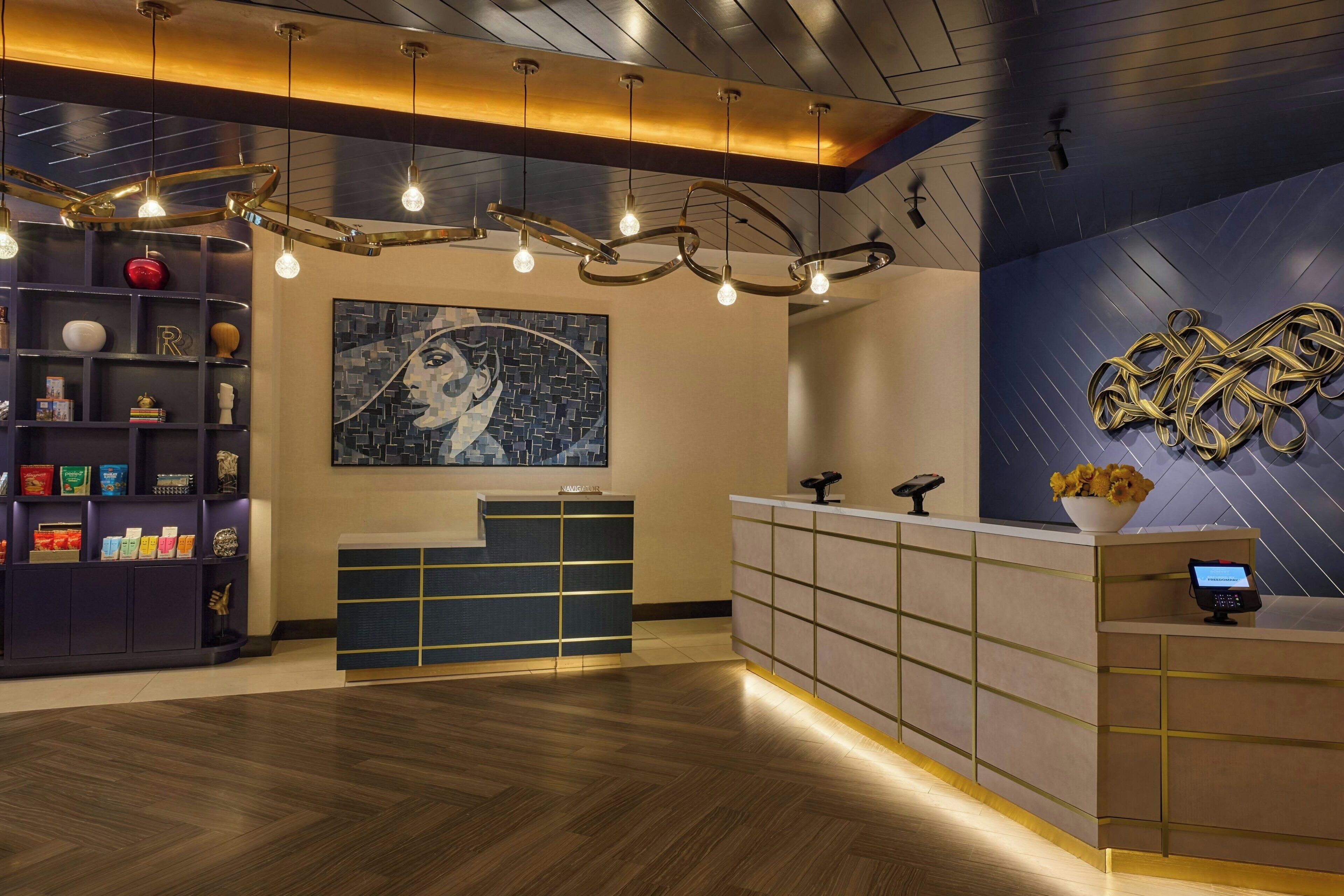 A reception area with a modern design, featuring a reception desk, a wall-mounted abstract art piece, and a decorative light fixture.