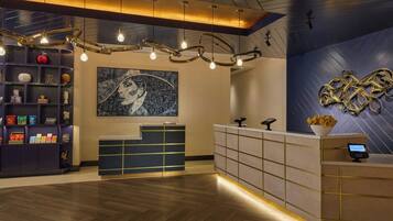 A reception area with a modern design, featuring a reception desk, a wall-mounted abstract art piece, and a decorative light fixture.