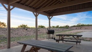 A covered picnic area with wooden benches and a barbecue grill. - Eagle's Den Suites Big Spring a Travelodge by Wyndham (Big Spring)
