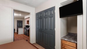 A compact kitchen with a dark grey door, a small island, and a built-in microwave. - Eagle's Den Suites Big Spring a Travelodge by Wyndham (Big Spring)
