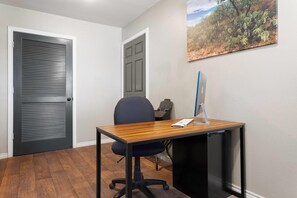 A room with a wooden desk, a black office chair, a computer, and a door with a window. - Eagle's Den Suites Big Spring a Travelodge by Wyndham (Big Spring)