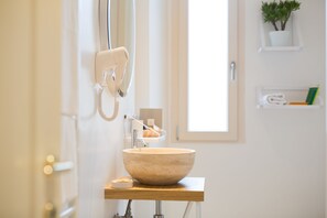 A bathroom with a large beige sink, a hairdryer, and a towel rack. - B&B Santa Maria del Fiore (Florence)