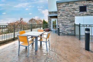 Un patio exterior con una mesa, sillas, un muro de piedra y vistas a la calle.