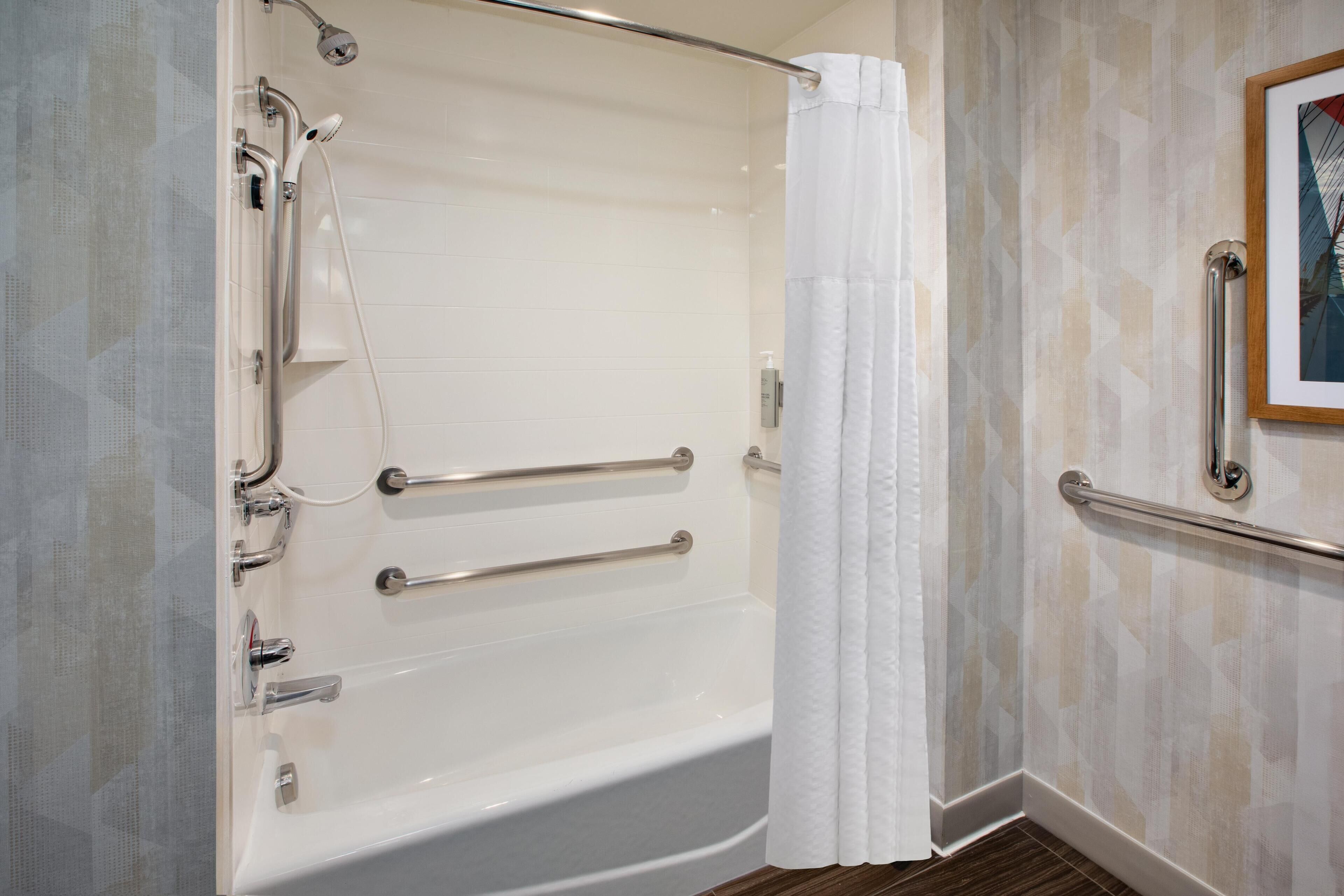 A modern bathroom with a walk-in shower, grab bars, and a framed picture on the wall.