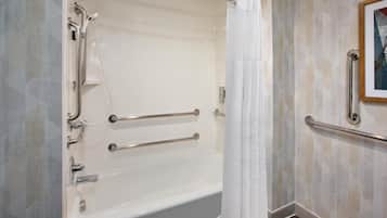 A modern bathroom with a walk-in shower, grab bars, and a framed picture on the wall.