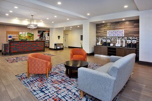 Vestíbulo de hotel con mostrador de recepción, zona de estar y estación de café.