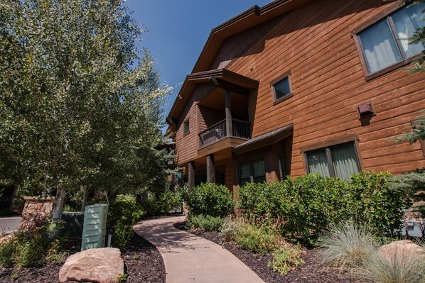 A multi-story wooden building with balconies and a pathway leading to the entrance.