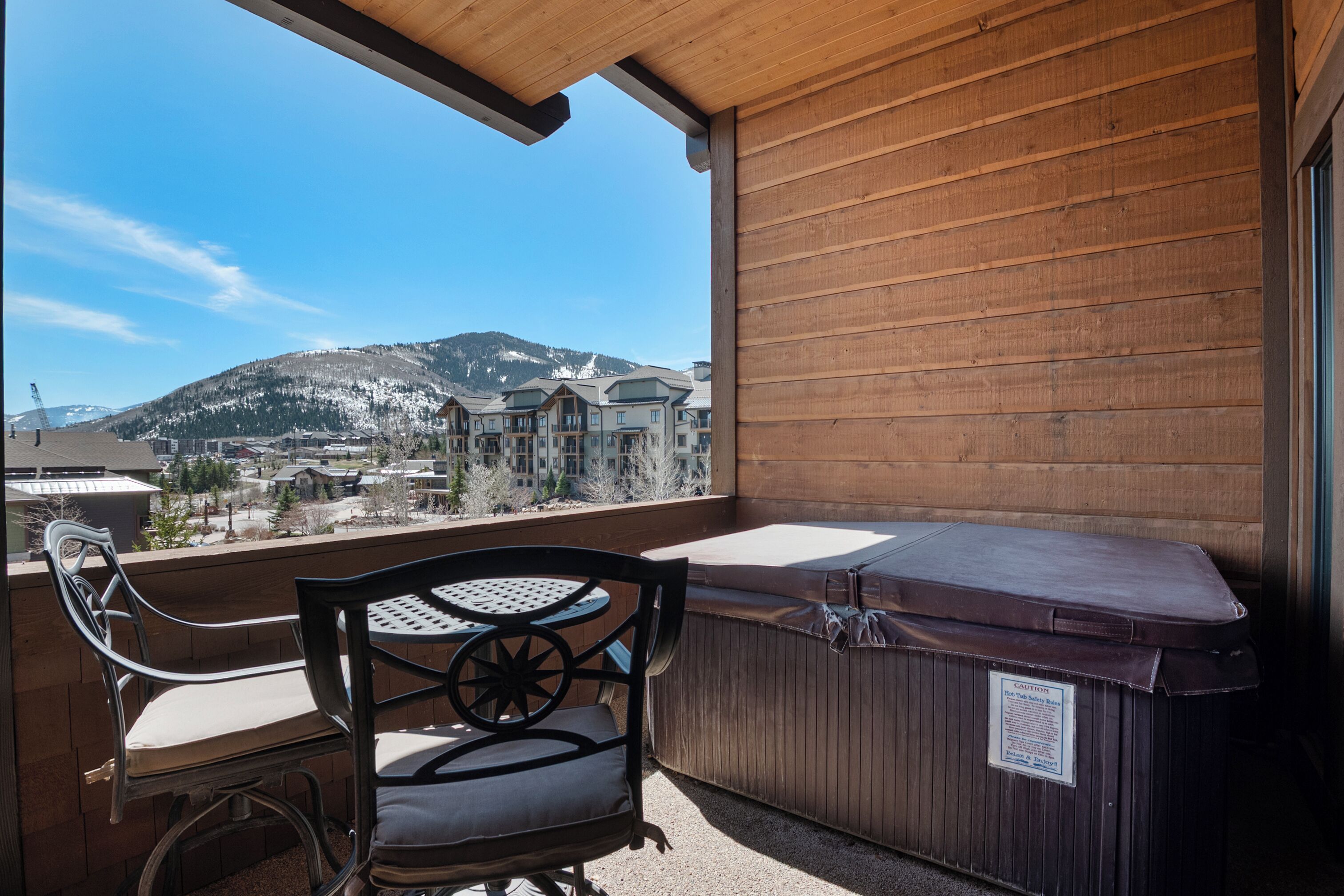Un balcon avec un mur en bois, un jacuzzi et une table avec des chaises.