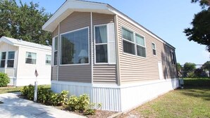 Una casa móvil de un piso con un ventanal grande y un porche pequeño.