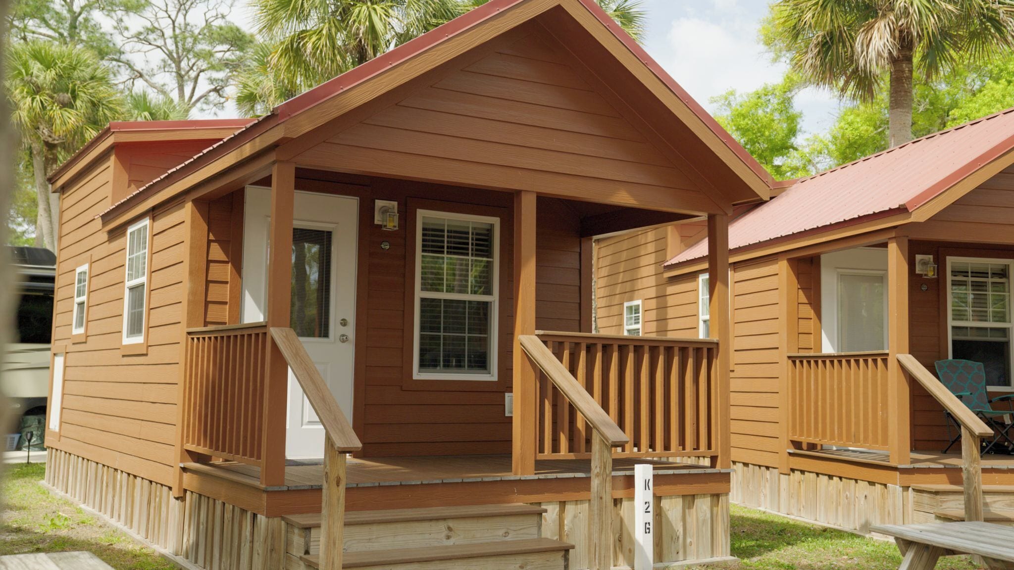 A wooden cabin with a porch, a front door, and a small deck area.