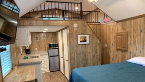 Habitación compacta con kitchenette, cama y una escalera que sube a un nivel superior.