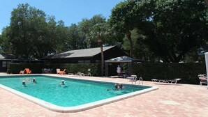 Una piscina rectangular con varias pistas, rodeada de sillas de descanso y sombrillas.