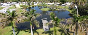 A lakeside property with a dock, palm trees, and RVs. - Road Runner Travel Resort - Caravan Park (Fort Pierce)