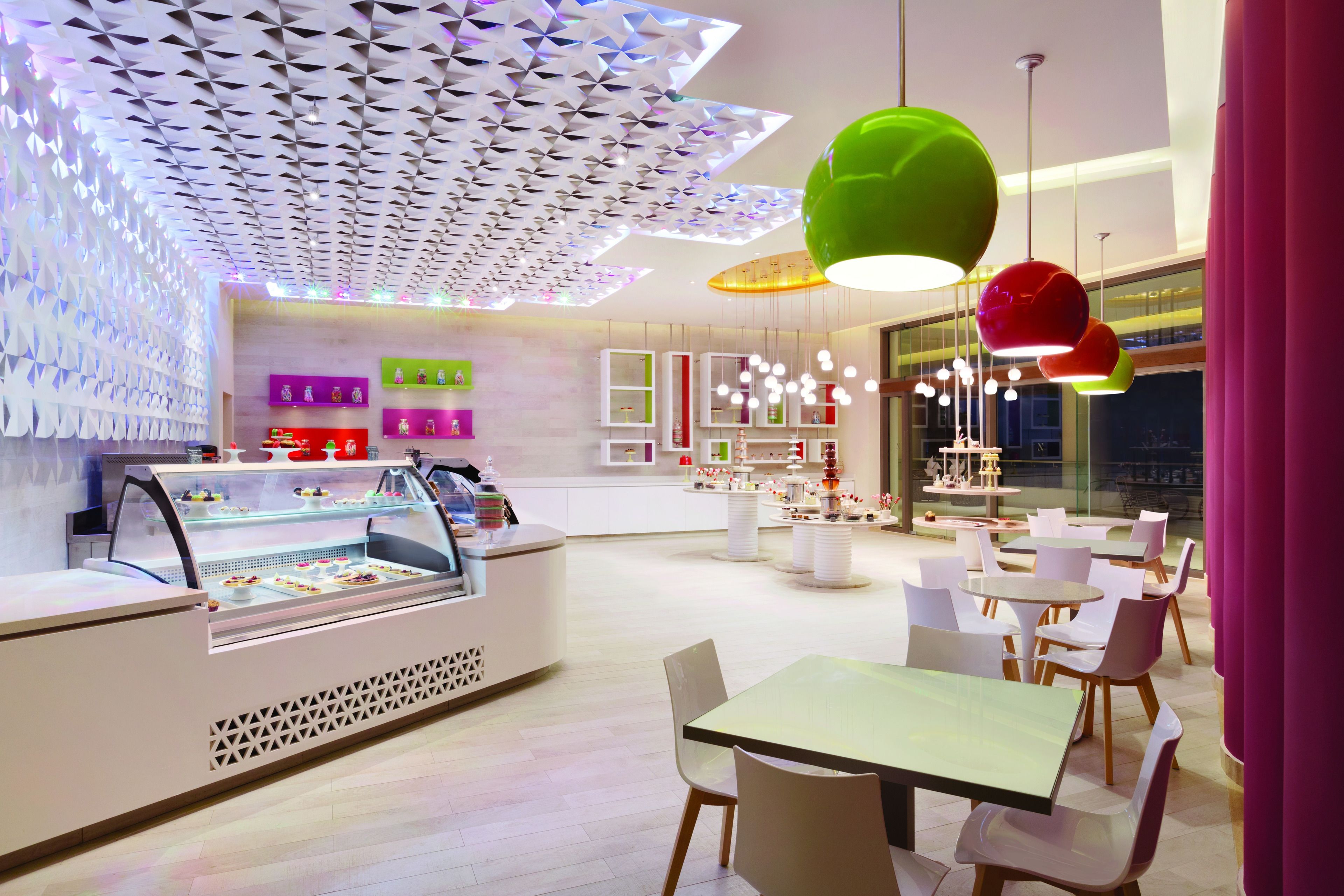 Una cafetería moderna con mostrador central, zona de estar e iluminación decorativa.